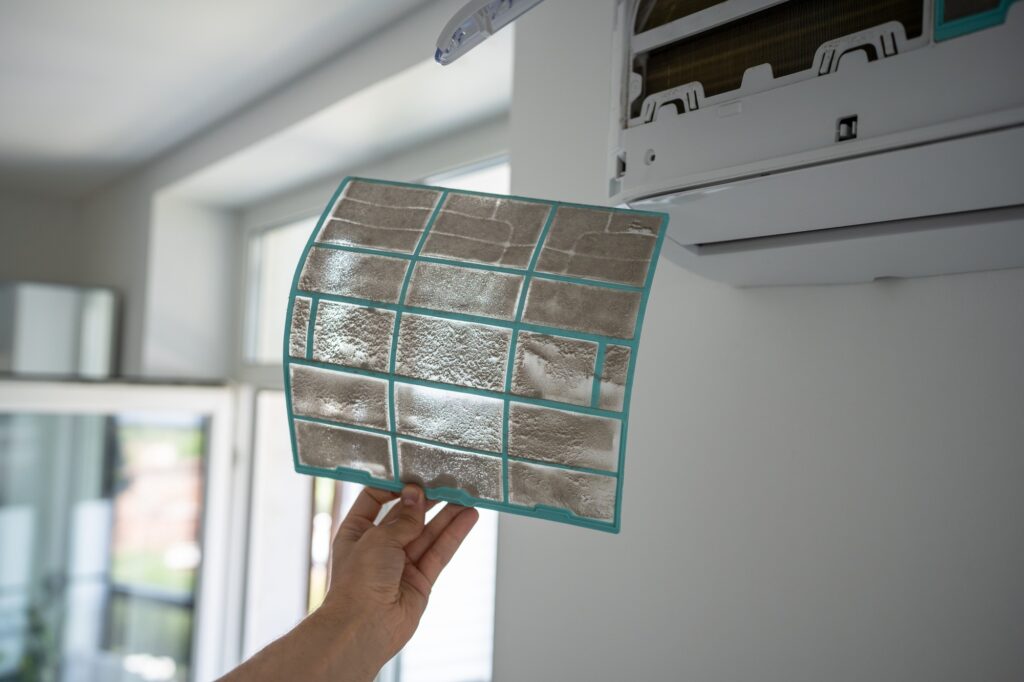 Male removing dirty dusty air conditioner coarse filter for washing, cleaning. Dust cause of illness